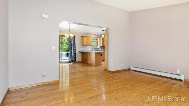 empty room with sink, light hardwood / wood-style flooring, baseboard heating, and a chandelier