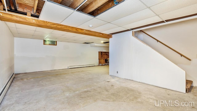 basement featuring a drop ceiling and a baseboard heating unit