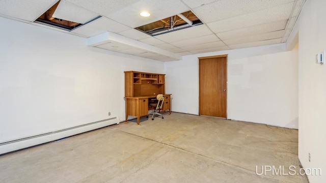 basement featuring a paneled ceiling and baseboard heating