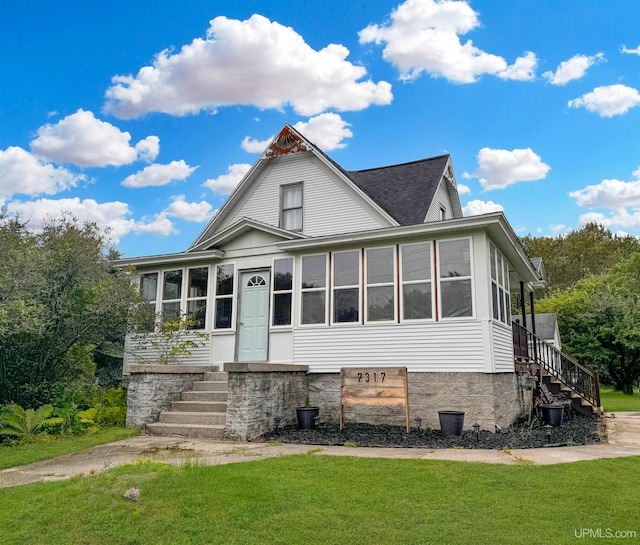 view of front of house with a front yard and a sunroom