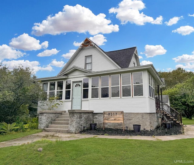 view of front facade with a sunroom and a front lawn