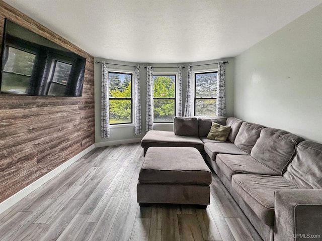 living room featuring wood walls, light hardwood / wood-style flooring, and a textured ceiling