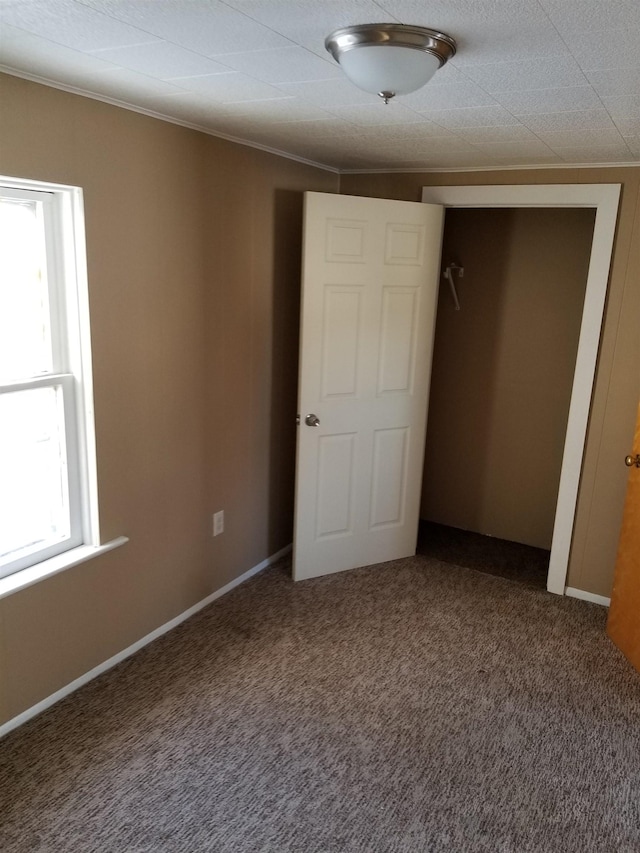 unfurnished bedroom featuring a closet, ornamental molding, and carpet floors