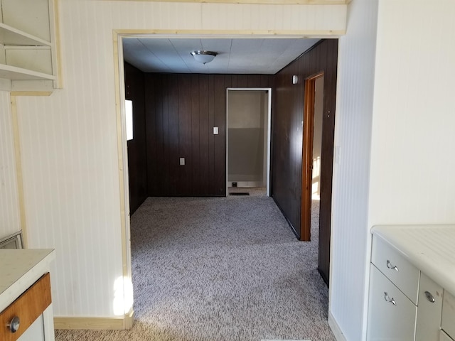 hallway featuring wooden walls and carpet floors