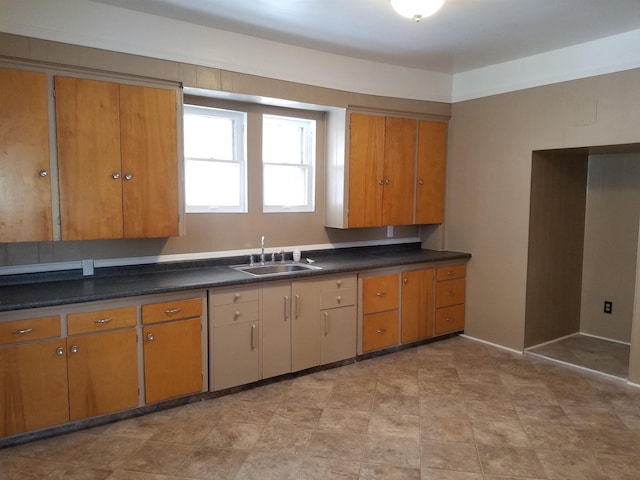 kitchen with a sink, dark countertops, and brown cabinets