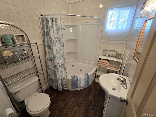 bathroom with tile walls, toilet, wood finished floors, shower / bathtub combination with curtain, and a sink