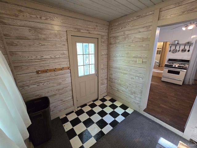 doorway with ceiling fan, hardwood / wood-style flooring, and wooden walls