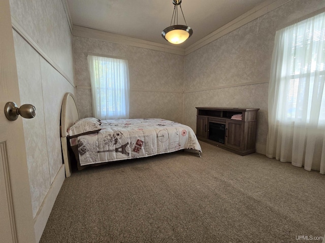 carpeted bedroom with ornamental molding and multiple windows