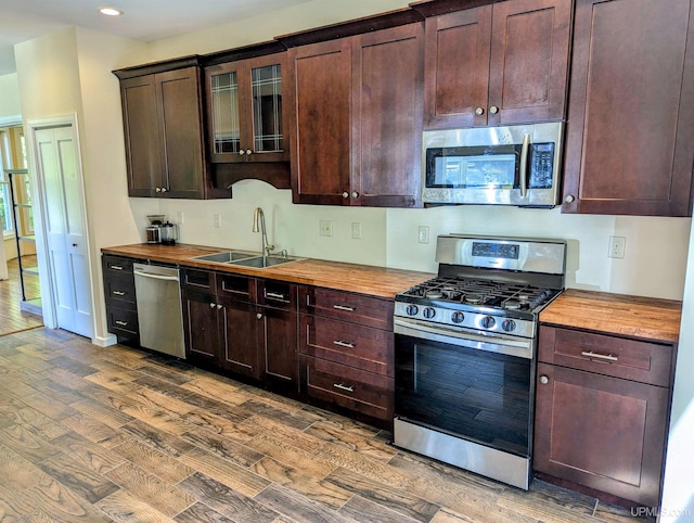 kitchen with appliances with stainless steel finishes, sink, dark hardwood / wood-style flooring, and wood counters