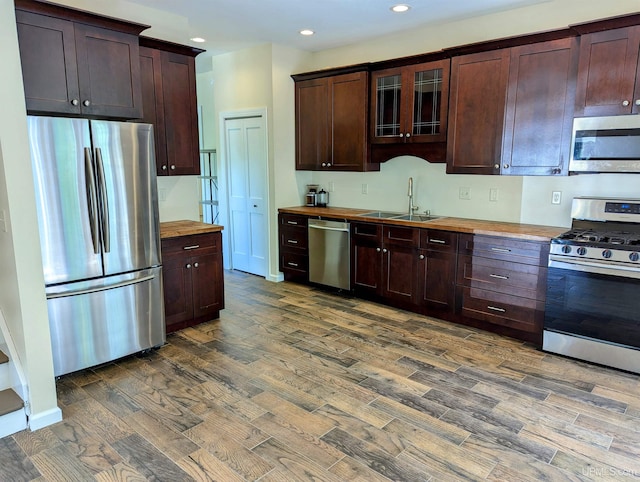 kitchen featuring dark hardwood / wood-style floors, appliances with stainless steel finishes, dark brown cabinetry, wood counters, and sink