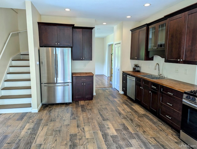 kitchen featuring dark hardwood / wood-style floors, appliances with stainless steel finishes, butcher block countertops, dark brown cabinetry, and sink