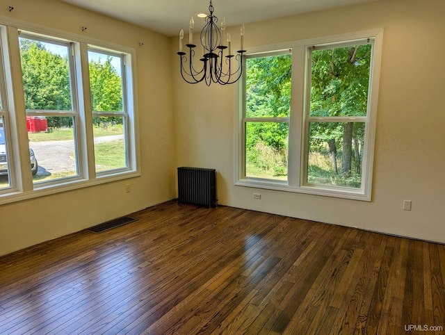 spare room featuring radiator heating unit, a notable chandelier, and dark wood-type flooring