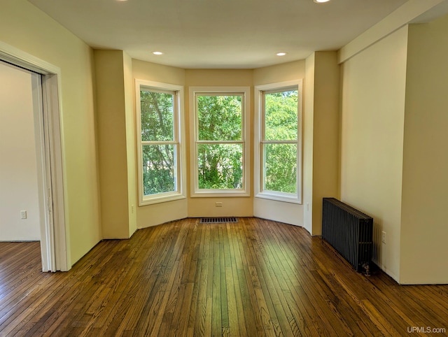 empty room with radiator heating unit and dark hardwood / wood-style floors