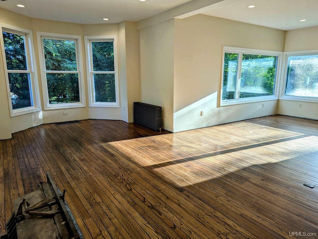 unfurnished living room with radiator, dark hardwood / wood-style flooring, and a wealth of natural light