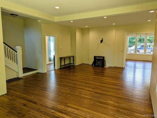 unfurnished living room with a wood stove and dark wood-type flooring