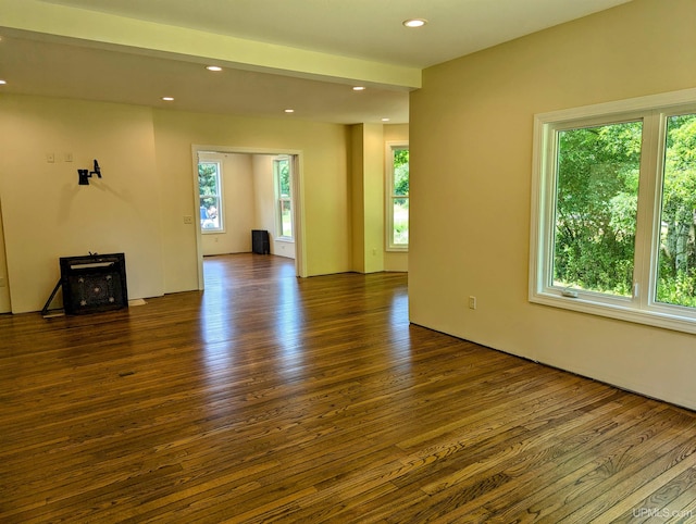 unfurnished living room featuring a wood stove, plenty of natural light, and dark hardwood / wood-style flooring