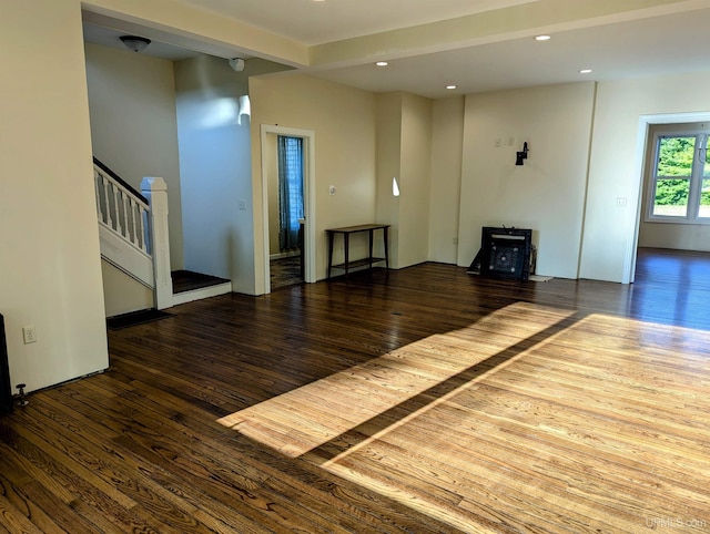 unfurnished living room with beamed ceiling and wood-type flooring