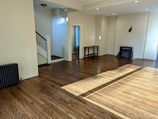 unfurnished living room featuring dark hardwood / wood-style flooring and radiator heating unit