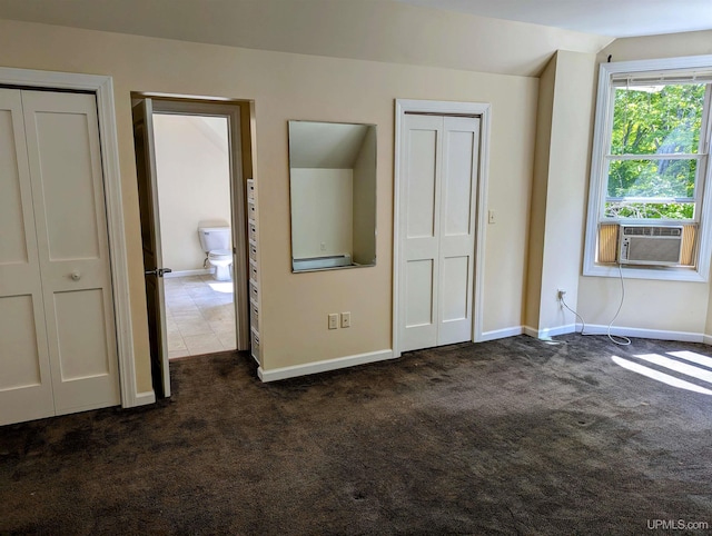 unfurnished bedroom with multiple closets, dark colored carpet, lofted ceiling, and cooling unit