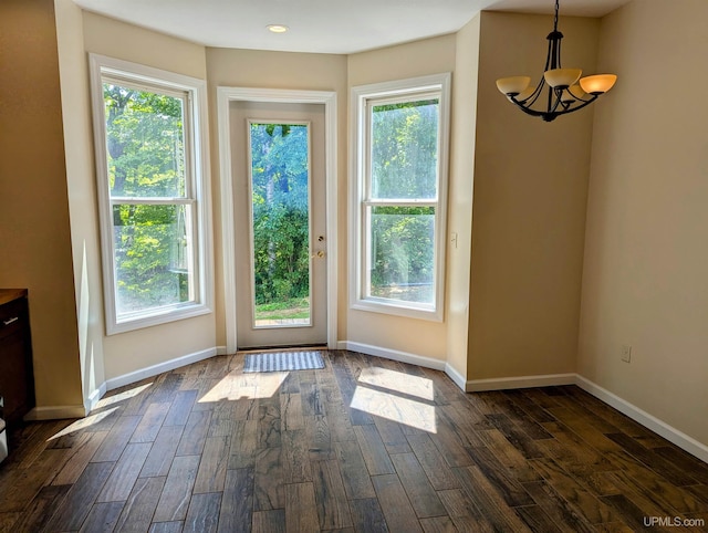 unfurnished dining area with dark hardwood / wood-style flooring, a chandelier, and a healthy amount of sunlight