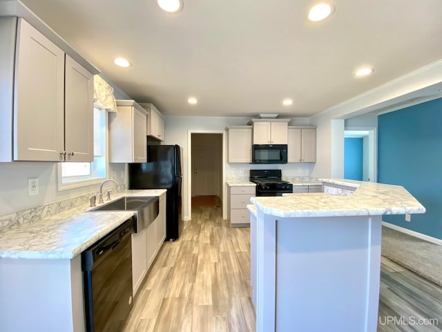 kitchen with a sink, black appliances, light wood-style flooring, and recessed lighting