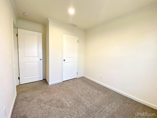 unfurnished bedroom with carpet floors, visible vents, baseboards, and ornamental molding