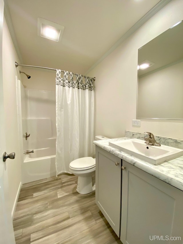 bathroom with toilet, ornamental molding, wood finished floors, vanity, and shower / bathtub combination with curtain