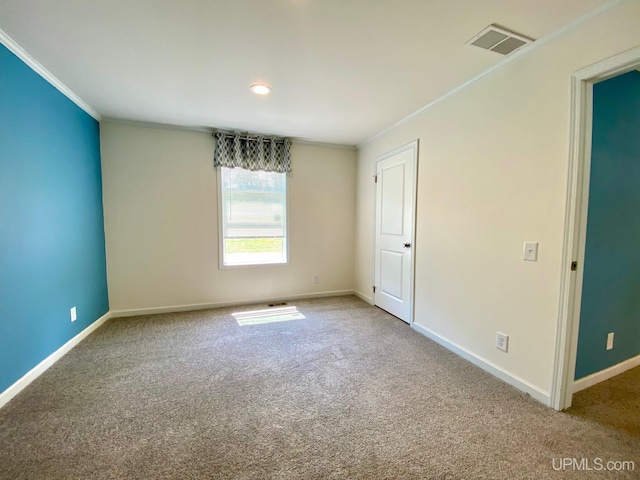 carpeted spare room featuring baseboards, visible vents, and ornamental molding