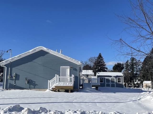 view of snowy exterior featuring a deck and an outdoor structure