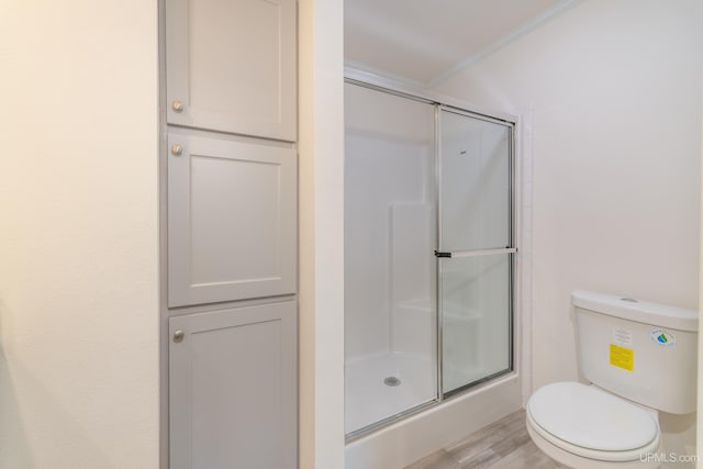 bathroom with a shower with door, toilet, and wood finished floors