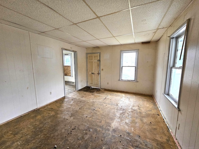 empty room with a paneled ceiling and a healthy amount of sunlight