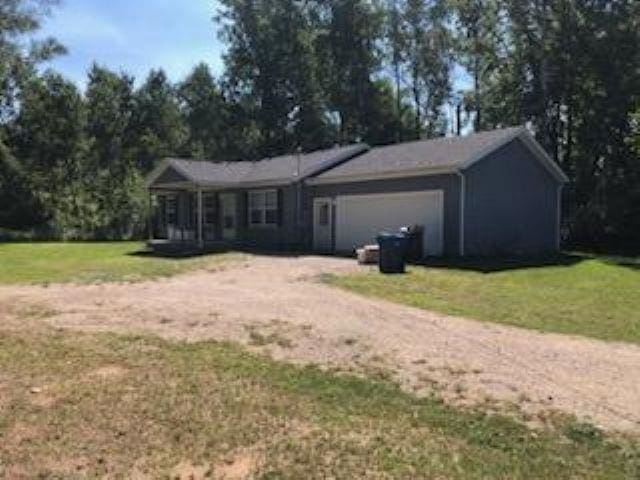 view of front of property featuring a front lawn, dirt driveway, and an attached garage