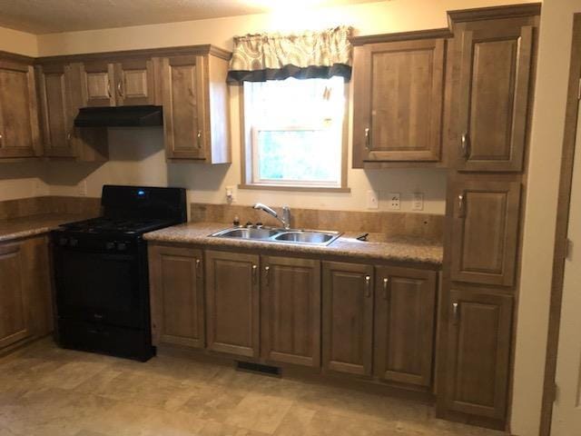 kitchen with light countertops, under cabinet range hood, a sink, and black range with gas stovetop