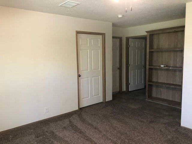 spare room featuring dark colored carpet and visible vents