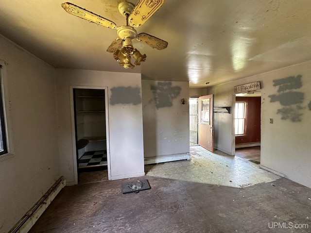 unfurnished bedroom featuring a walk in closet, a closet, ceiling fan, and baseboard heating