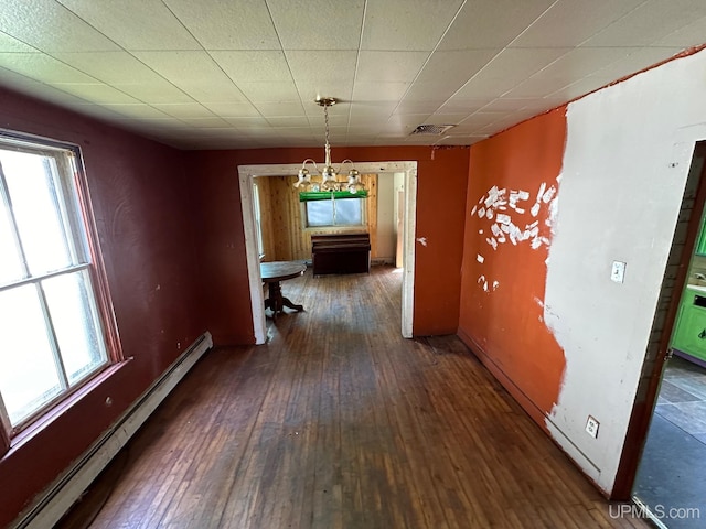 unfurnished dining area with dark wood-type flooring, a baseboard heating unit, and plenty of natural light