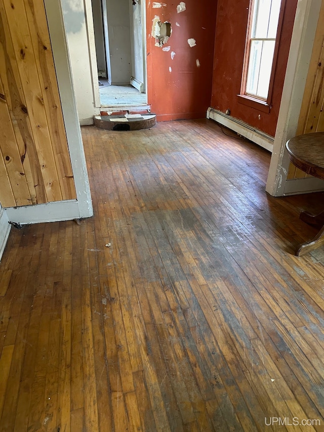 interior space featuring wooden walls, a baseboard radiator, and dark hardwood / wood-style floors