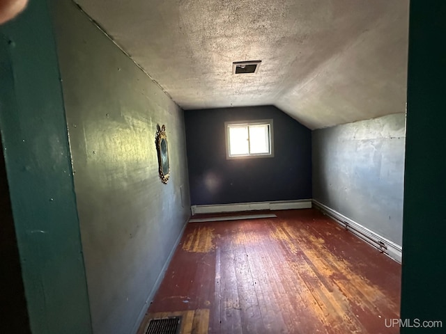 additional living space featuring baseboard heating, wood-type flooring, a textured ceiling, and vaulted ceiling