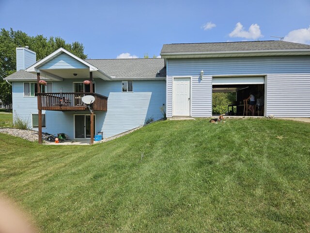 back of property featuring a lawn, a garage, and a wooden deck