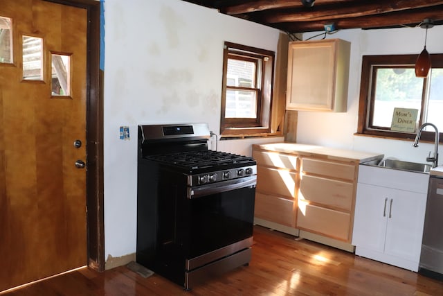 kitchen featuring pendant lighting, hardwood / wood-style floors, gas stove, sink, and beam ceiling