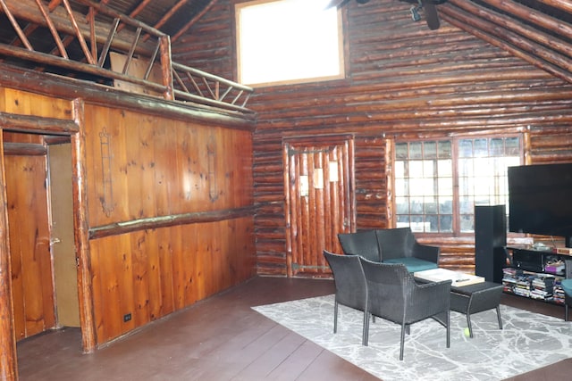 living area with rustic walls, high vaulted ceiling, and hardwood / wood-style flooring