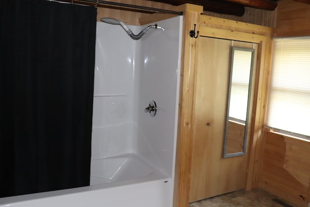 bathroom featuring shower / bath combo, wood walls, and a healthy amount of sunlight