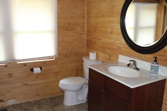 bathroom with tile patterned floors, vanity, wooden walls, and toilet