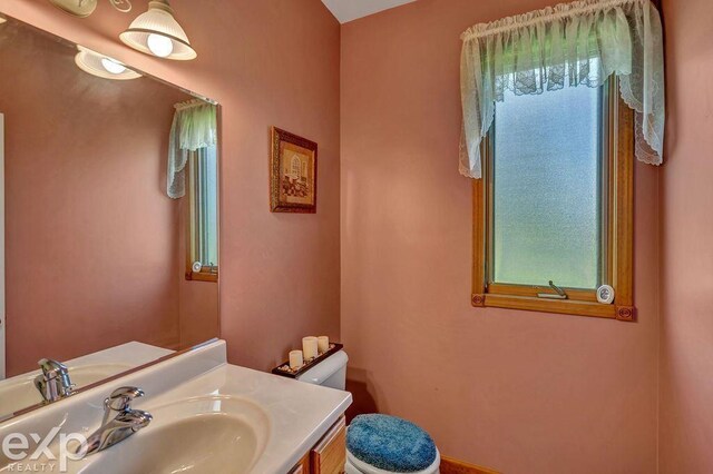 bathroom featuring vanity, a healthy amount of sunlight, and toilet