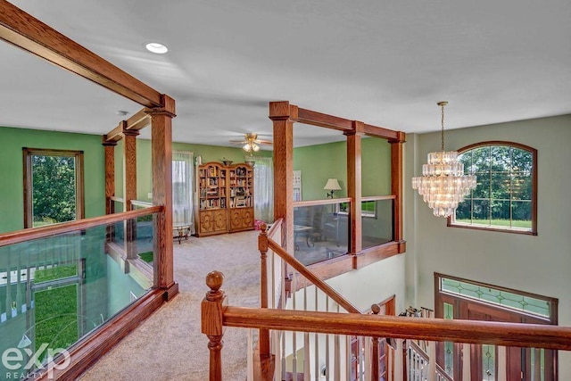 hall with plenty of natural light, a chandelier, and carpet