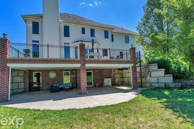 rear view of property with a lawn, a patio, and a balcony