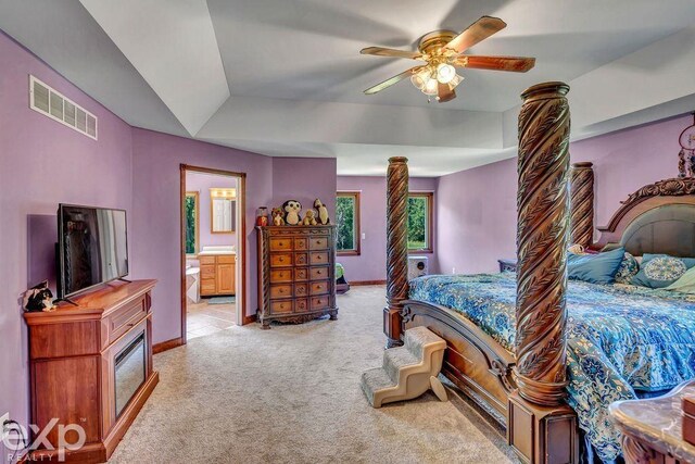 carpeted bedroom featuring connected bathroom, a tray ceiling, and ceiling fan