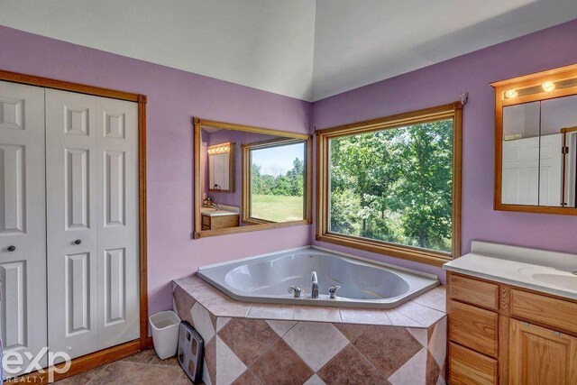 bathroom with tile patterned floors, vanity, and tiled bath