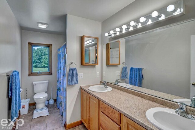 bathroom with tile patterned floors, double sink vanity, and toilet