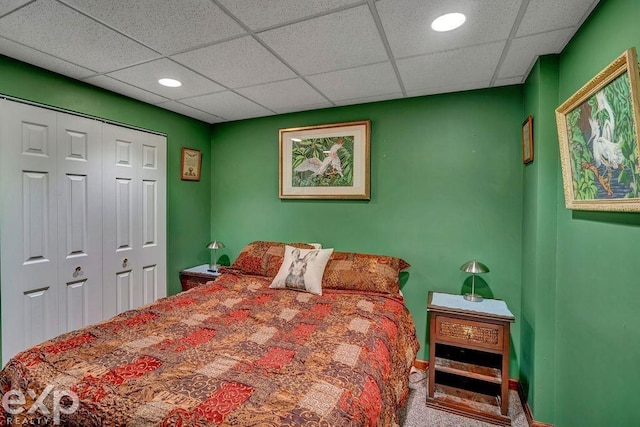 bedroom with a paneled ceiling, carpet flooring, and a closet